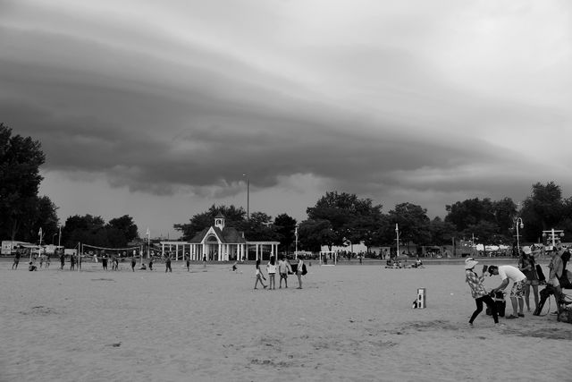 Families on the beach at Victoria Park in Cobourg under a sweeping cloudy sky